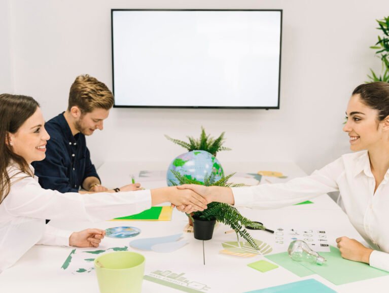 two-happy-businesswomen-shaking-hands-desk
